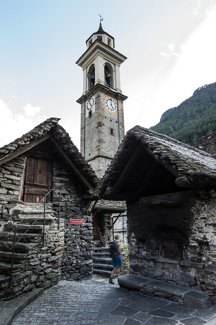 Young female hiker walking through an old village, Valle Verzasca, Ticino, Switzerland