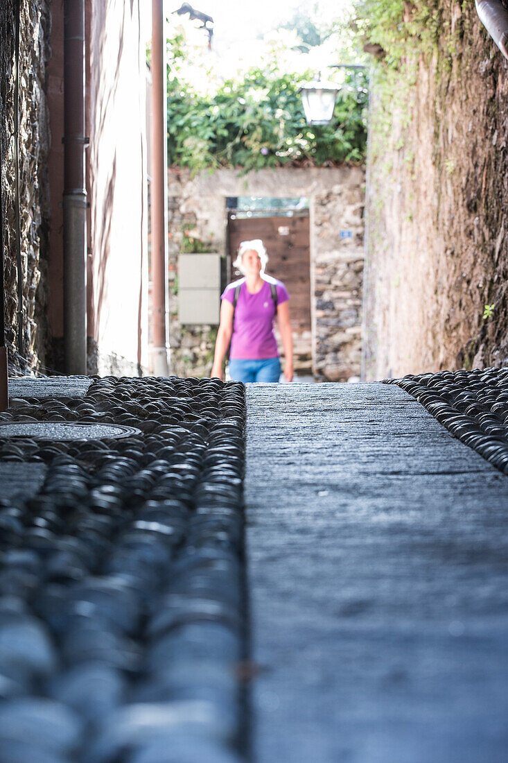 Young female hiker walking through an old town, Ronco, Ticino, Switzerland