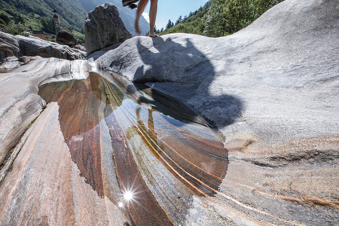 Young female hiker walking on rocks between a river, Valle Verzasca, Ticino, Switzerland