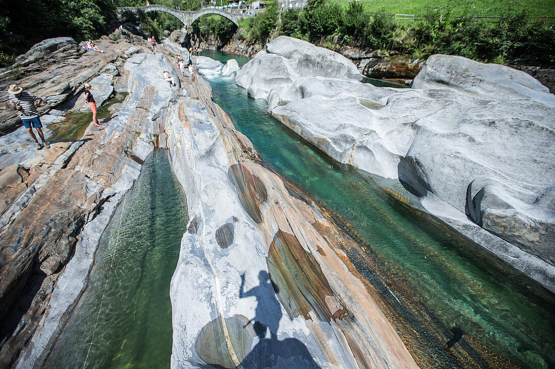 Touristen an einem Fluss bei einer alten Brücke, Val Verzasca, Tessin, Schweiz