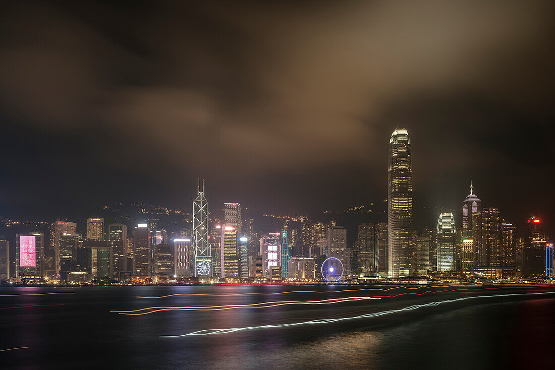 Blick auf Central – Hongkongs Finanzdistrikt – bei Nacht während Schiffe durch den Hafen fahren, Kowloon, Hongkong, China, Asien