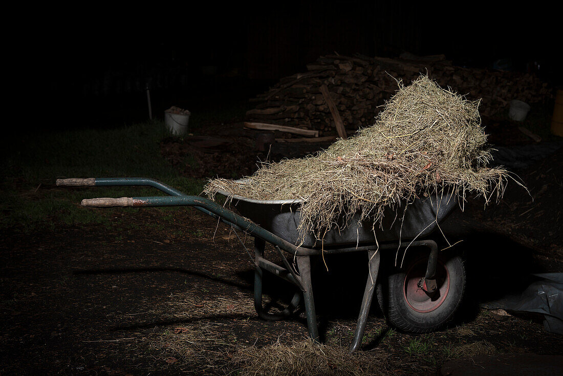 wheelbarrow packed with straw in front of kiln at night, charcoal production, Aalen, Baden-Wuerttemberg, Germany