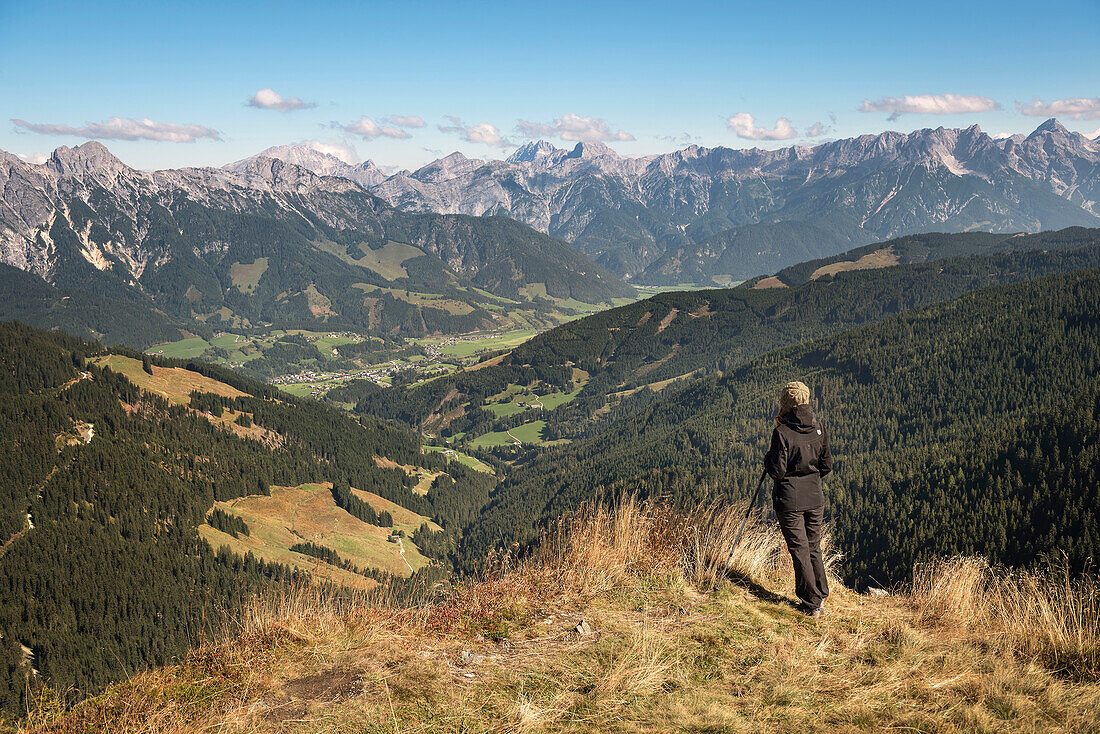 Junge Wanderin rastet mit Wanderstöcken und genießt den Blick auf Leogang und die Bergkette, Salzburger Land, Österreich, Europa