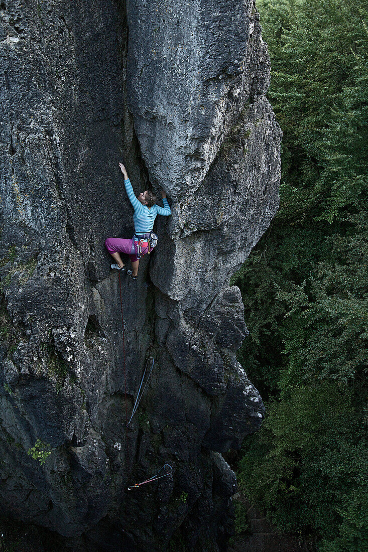 Young woman climbing at a rock face, Pottenstein, Franconia, Germany