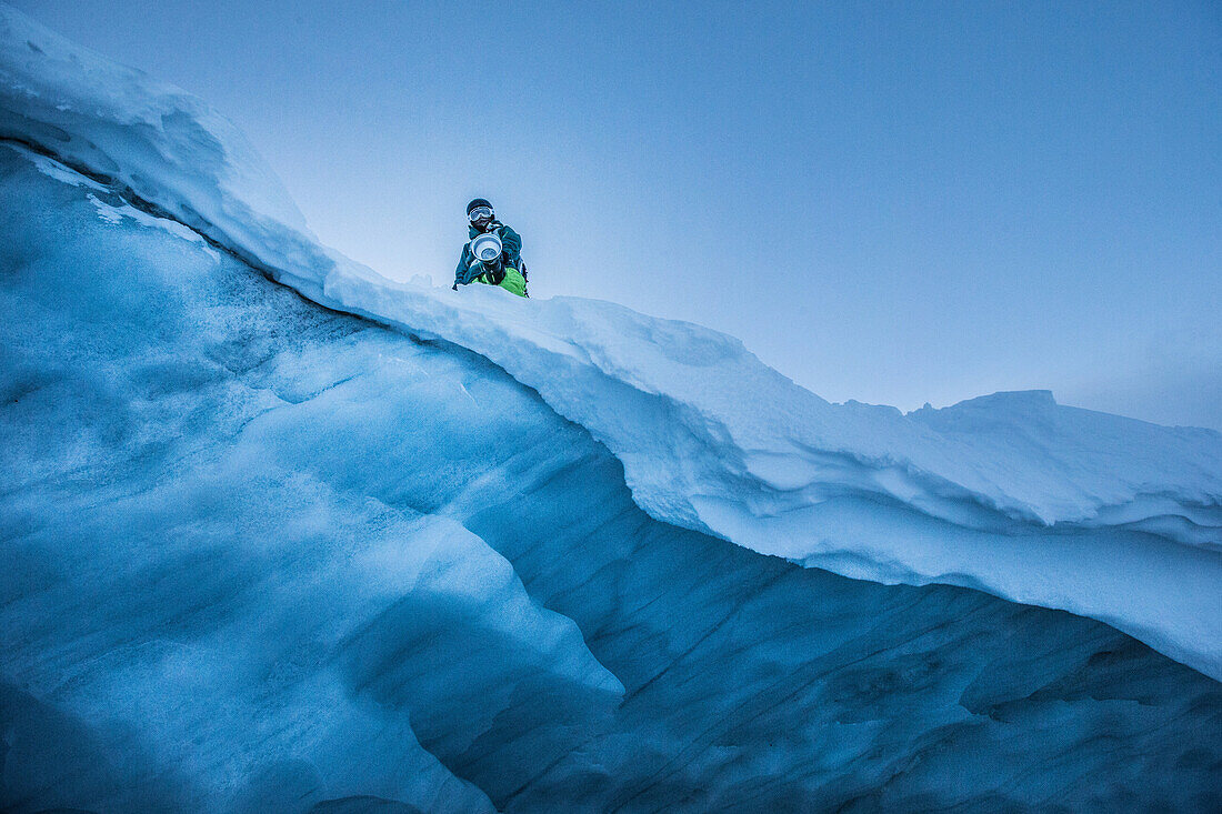 Junger Snowboarder hält einen großen Fotoblitz auf einem Gletscher, Pitztal, Tirol, Österreich