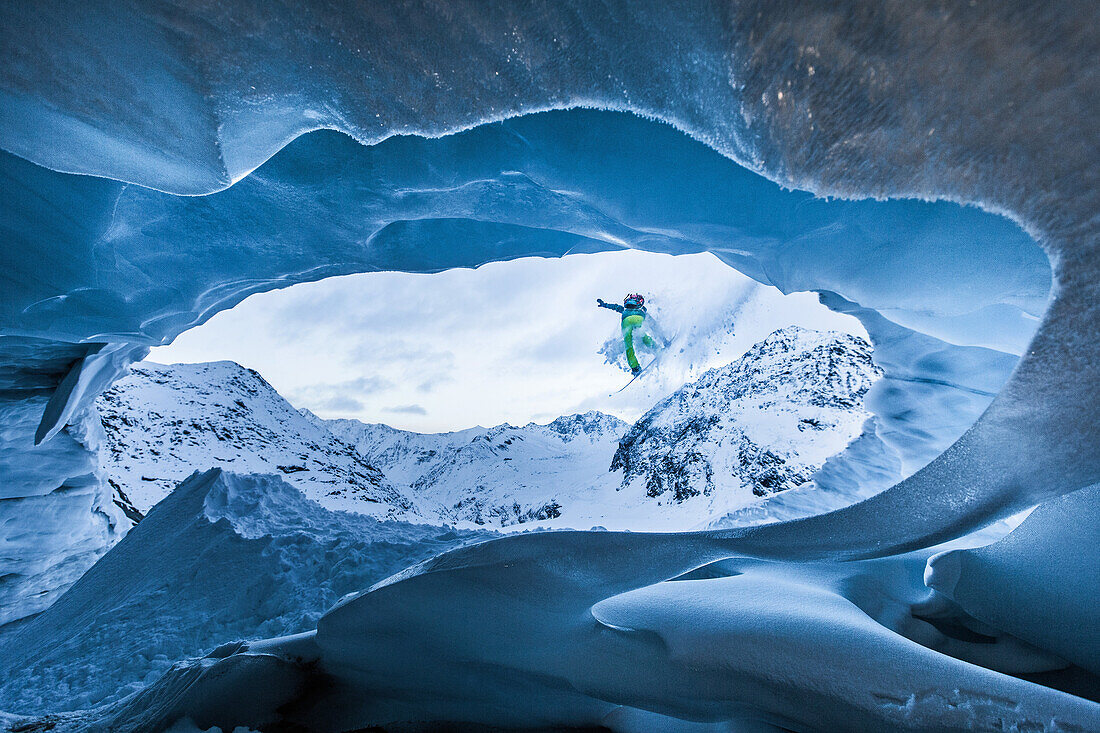 Young male snowboarder jumping down from a cave of a glacier, Pitztal, Tyrol, Austria