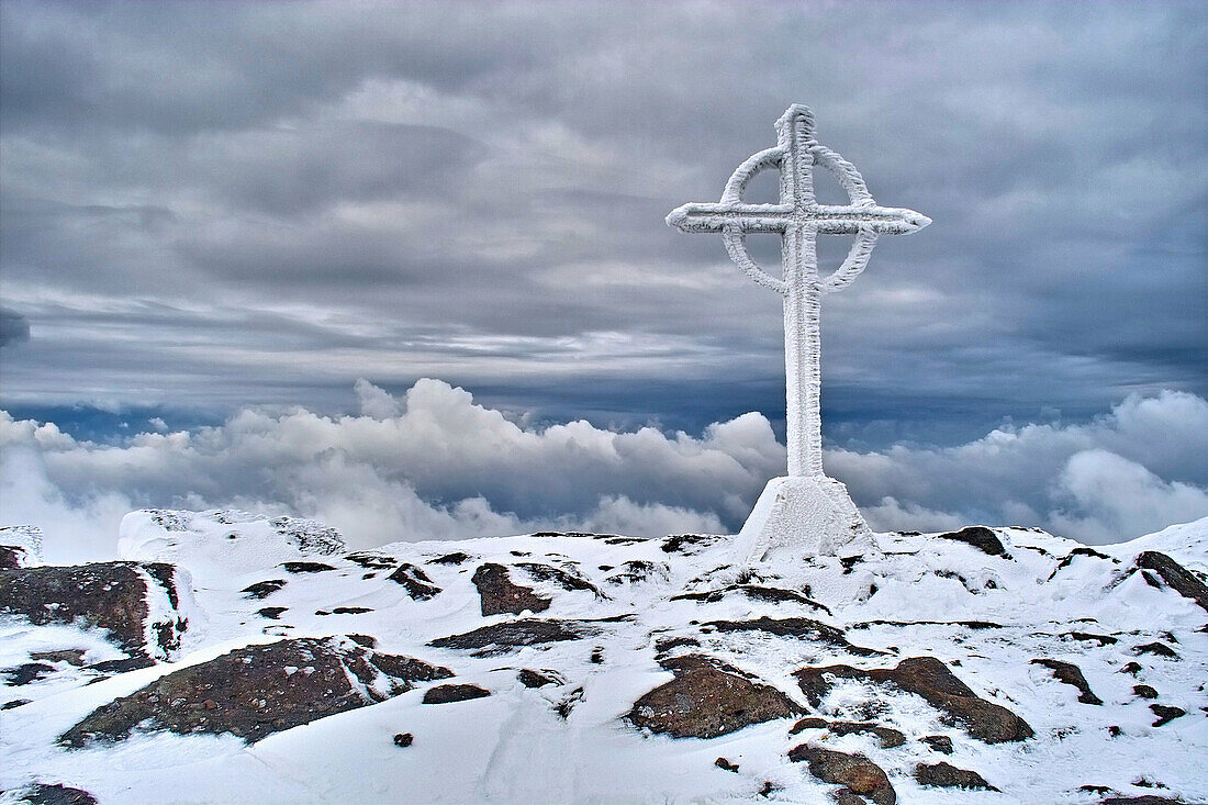The summit cross on the snow covered summit of Galtymore, Galtee Mountains, County Tipperary, Ireland.