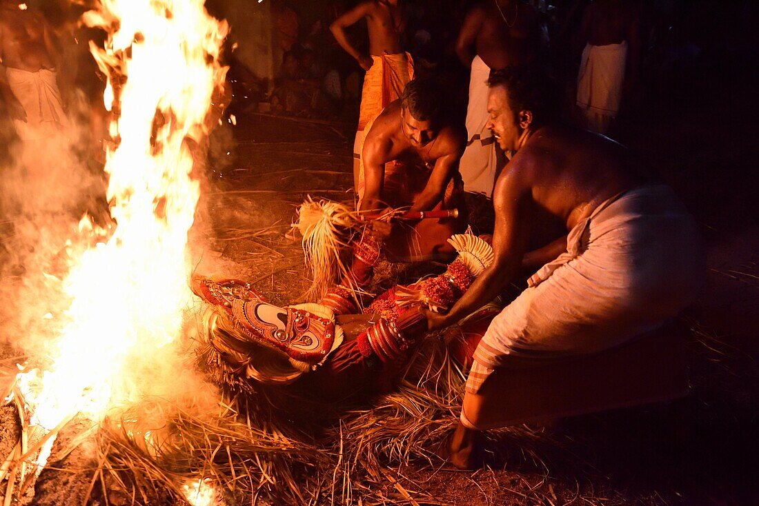 India, Kerala, Kannur region, Mundiyat Bhagavathi temple, Pottan Theyyam lying and burning (!) on a pyre.