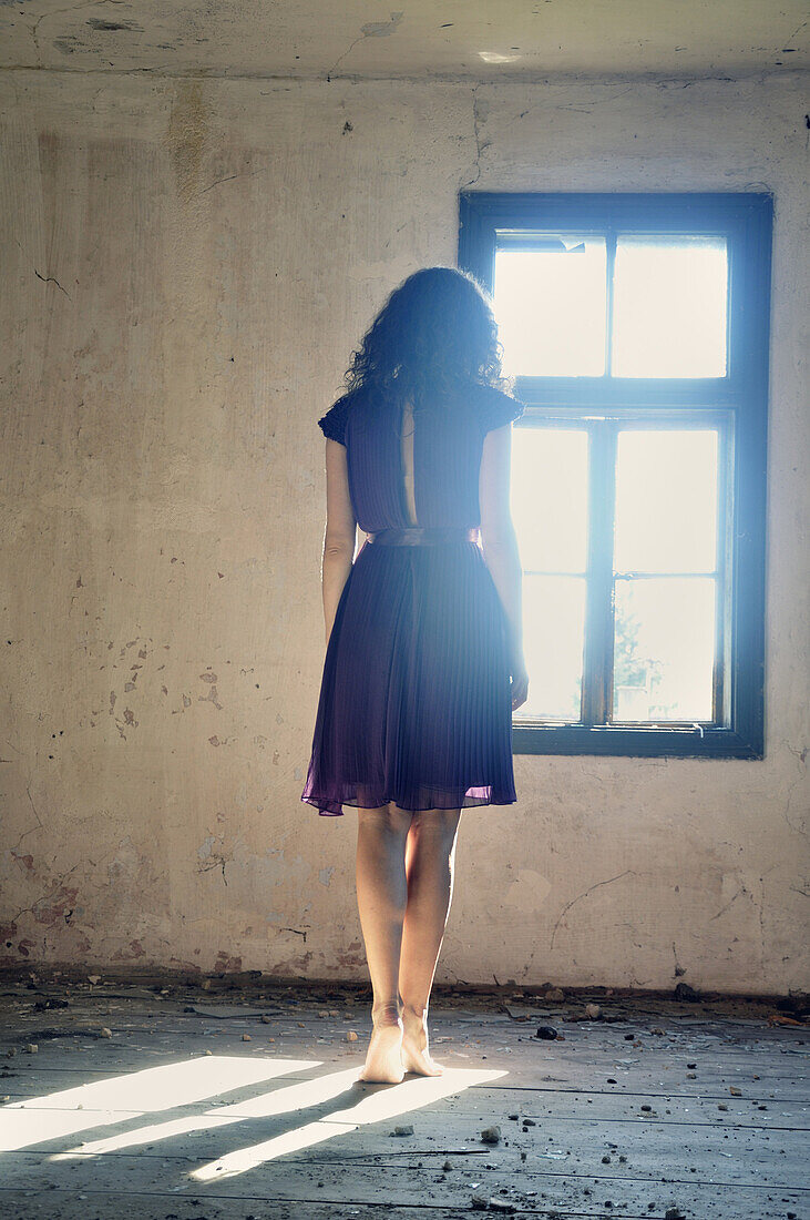 Young woman standing by the window.