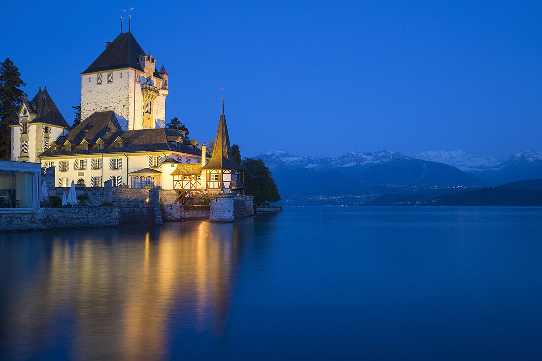 Oberhofen Castle at Lake Thun with mountains at night, Oberhofen, Switzerland.