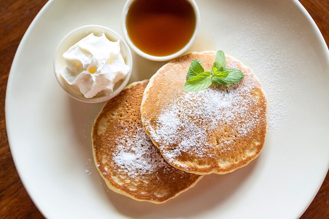 Two pancakes with maple syrup and whipped cream.