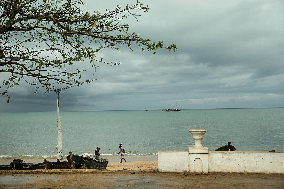 Zwei einheimische Mädchen gehen am Strand an zwei einfachen Fischerbooten vorbei, Sao Tome, Sao Tome und Príncipe, Afrika