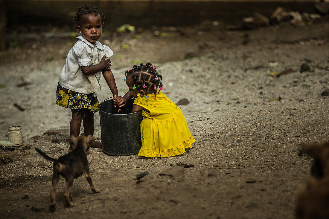 Zwei kleine einheimische Mädchen waschen ihre Hände in einem Eimer, Sao Tome, Sao Tome und Príncipe, Afrika