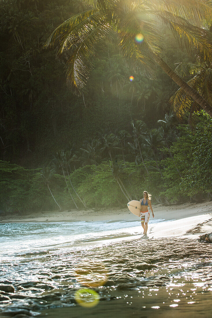 Young female surfer walking at the beach, Sao Tome, Sao Tome and Principe, Africa