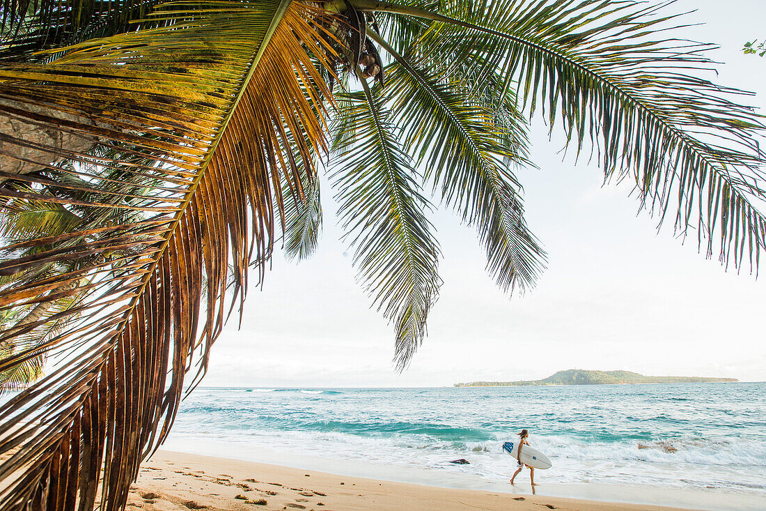 Young female surfer walking at the beach, Sao Tome, Sao Tome and Principe, Africa