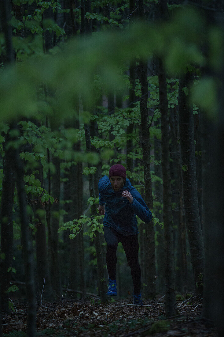 Young man running on a trail through a forest, Allgaeu, Bavaria, Germany