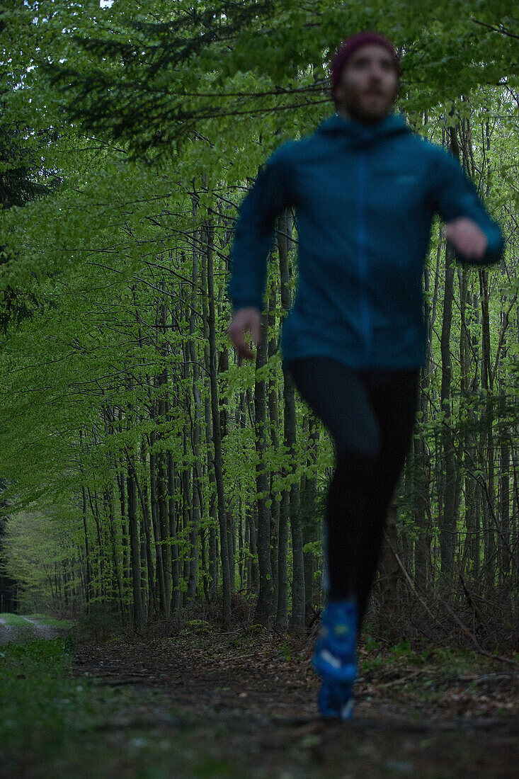 Young man running on a trail through a forest, Allgaeu, Bavaria, Germany