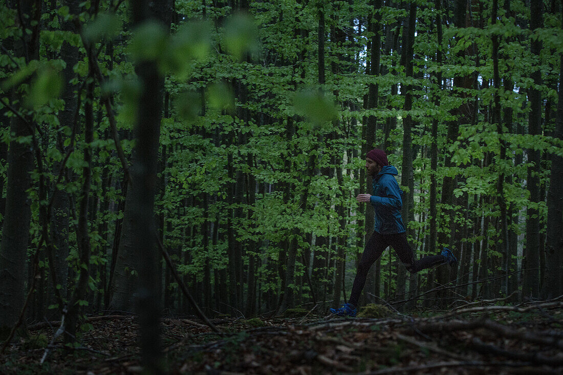 Junger Mann läuft auf einem Weg durch einen Wald, Allgäu, Bayern, Deutschland