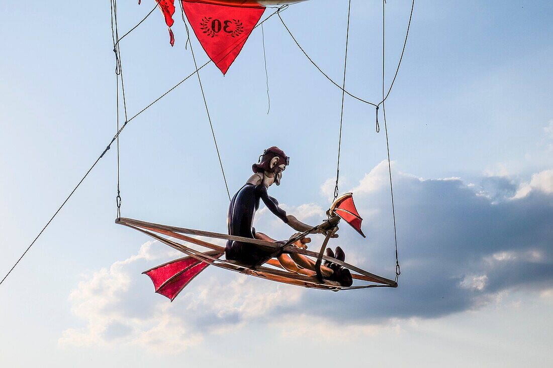 Eine Puppe rudert in einem Boot unter einem Luftballon am Himmel.