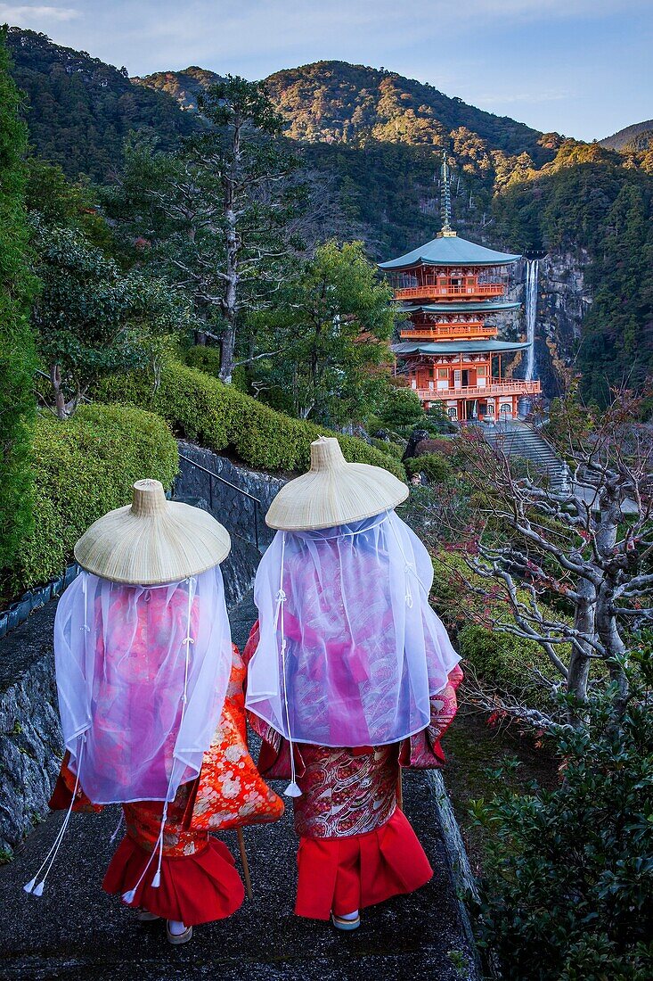 Pilgrims in Heian period costumes and Nachisan Seiganto-ji Temple (Three-Storied Pagoda), near Kumano Nachi Taisha Grand Shire, Kumano Kodo, Nakahechi route, Wakayama, Kinki, Japan.