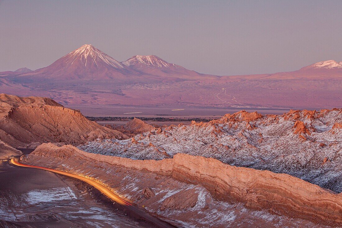 Valle de la Luna (Valley of the Moon ), in background at left volcanoes Licancabur and Juriques with snow on top, and salt deposited on the nearest mountains, Atacama desert. Region de Antofagasta. Chile.
