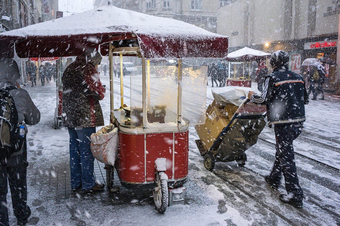 A hot chestnut stall during winter snow storm on Istiklal Caddesi, Beyoglu, Istanbul, Turkey,.