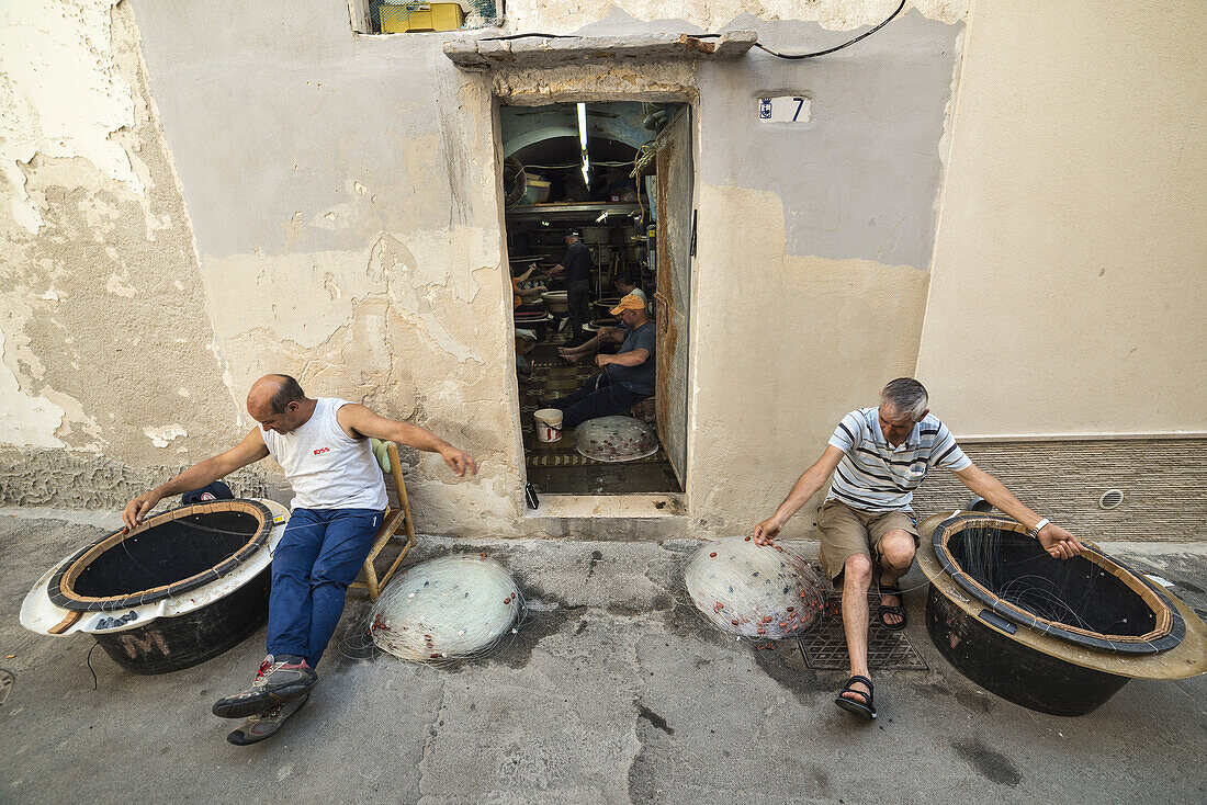 Fishermen preparing their fishing lines in the old town of Gallipoli, Puglia, Southern Italy.