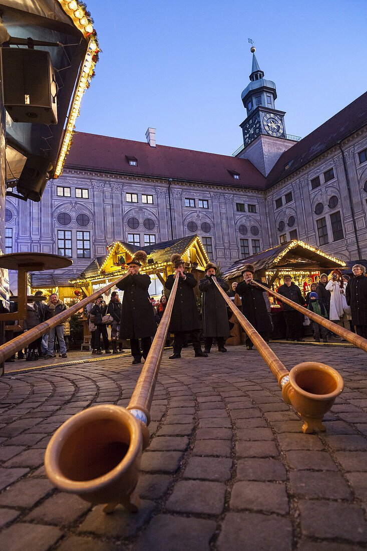 Christmas market in Munich. The alpine Christmas Village in the Kaiserhof of the Residenz, the palace of the bavarian kings. Concert with Alpenhorn (Alphorn). Europe, Germany, Bavaria, Munich, December 2013.
