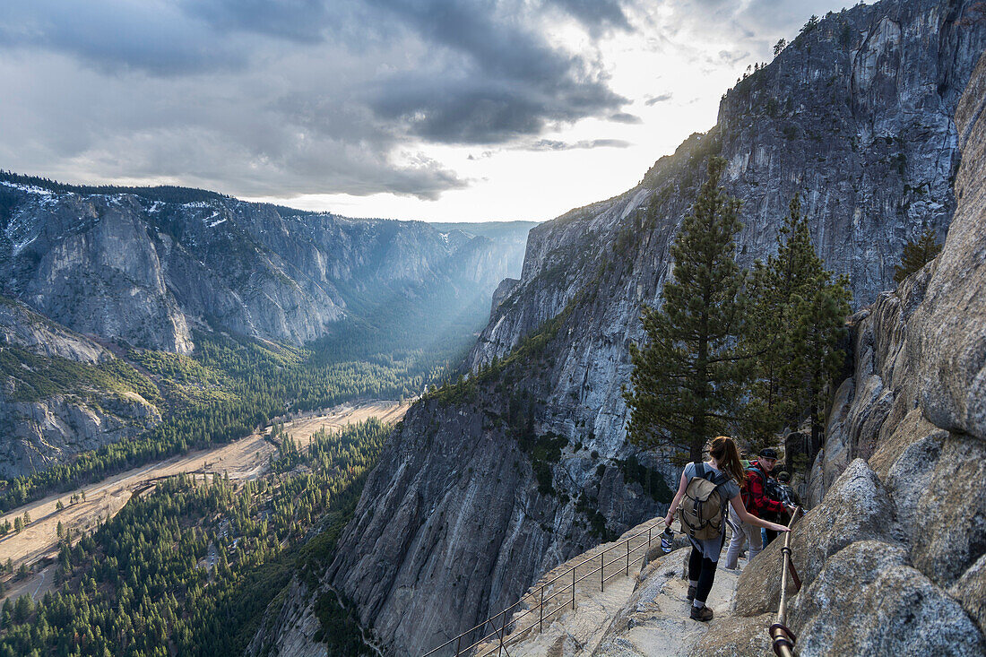 Group of hikers going down to Yosemite Point with the amazing view of the valley and the sunset, California, USA.