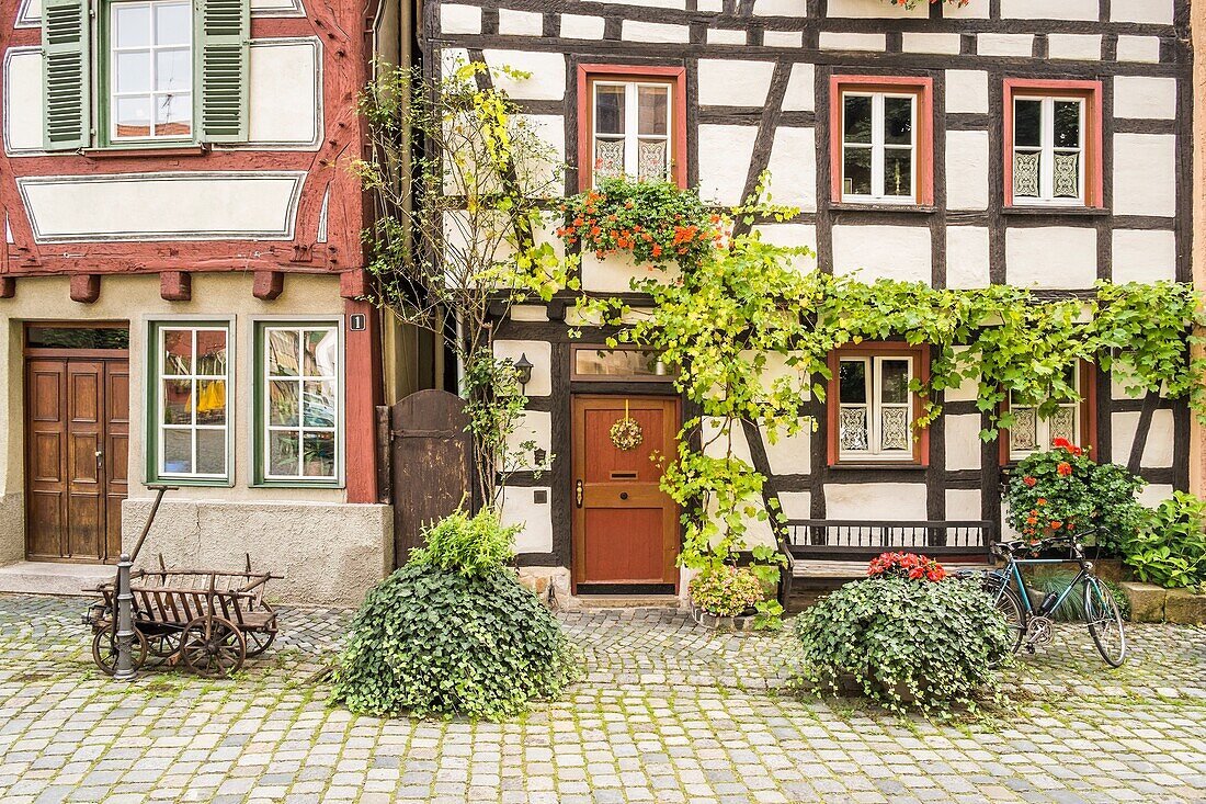 bicycle and historic hand waggon in front of the flowerdecked facade of half timbered houses in the historic part of esslingen, baden-wuerttemberg, germany.