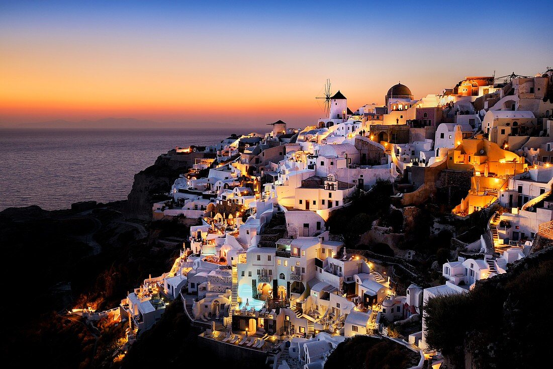 Windmills and village of Oia at sunset. Greece, Greek islands in the Aegean sea, the Cyclades, Santorini island (Thera, Thira).