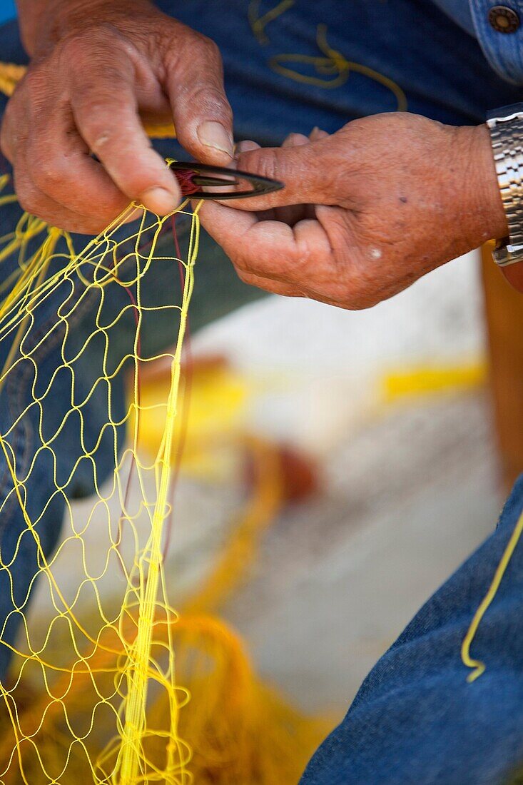 Fisherman repairing fishing net at the port, Mykonos, Cyclades Islands, Greek Islands, Greece, Europe.