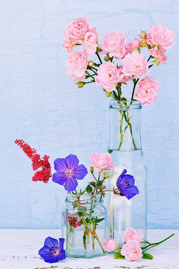 Glass containers filled with Geranium, Astilbi and miniture Rose flowers.