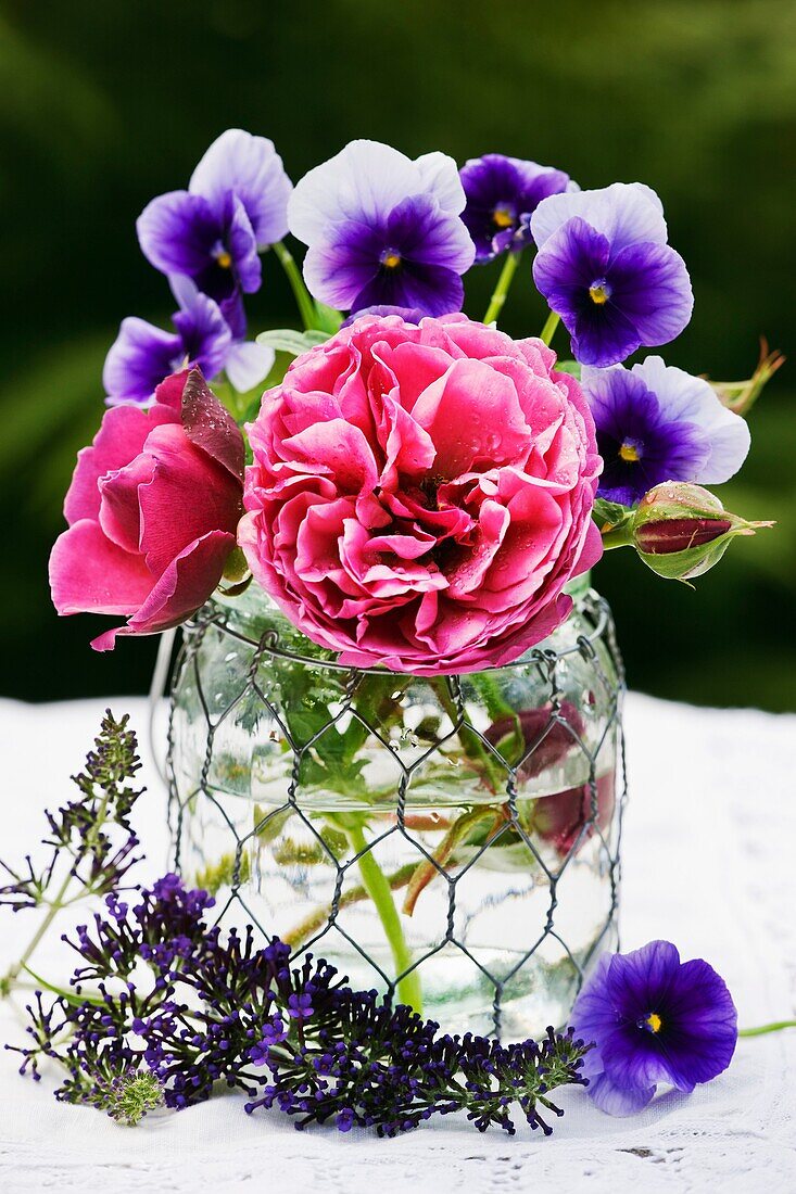 Rosen und Viola-Blüten in einer Glasvase