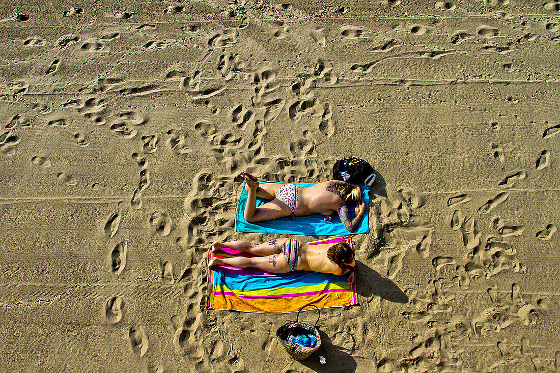 'Two girls, siesta on beach, Salinas, Asturias; Spain.'