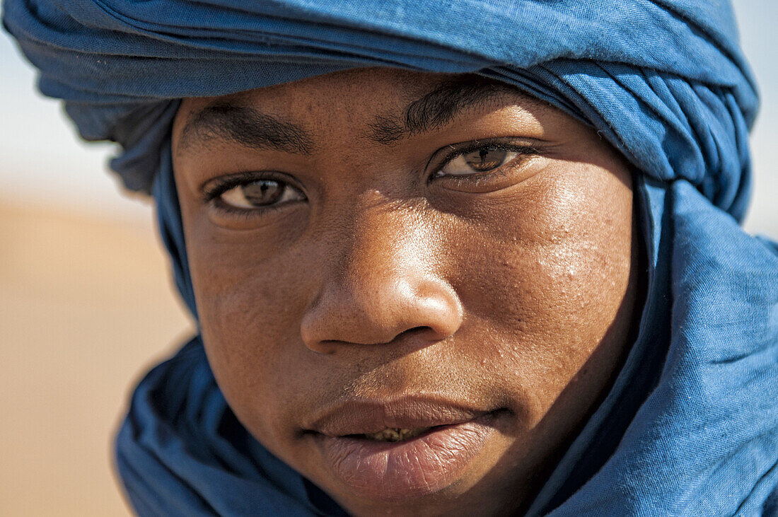 Portrait of Berber boy in Tinfou dunes near Tamegrout, Zagora, Draa Valley, Morocco.