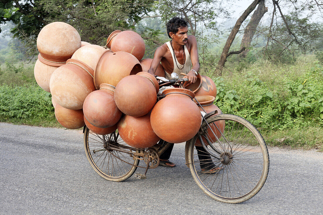 Tribal man carrying pots to the market on a bicycle. Kurmali tribe. Bokaro District Jharkhand, India.
