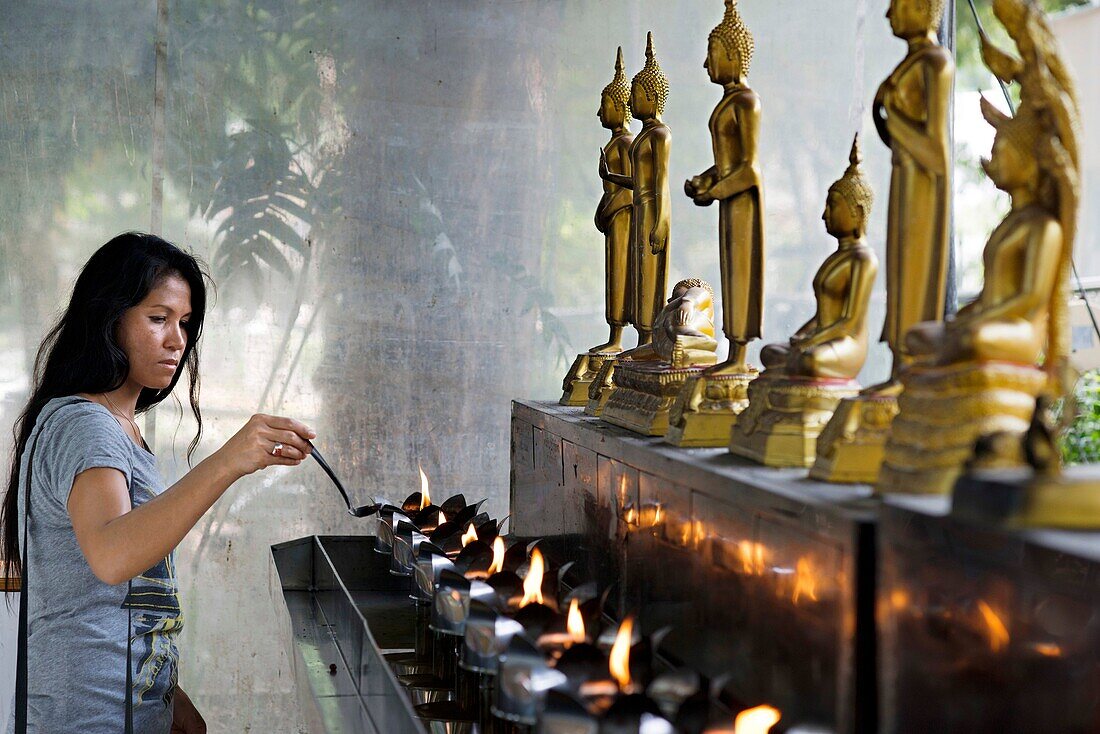 Woman praying in Wat Patum Wanaram Tample. Bangkok. Wat Pathum Wanaram is a Buddhist temple in Bangkok, Thailand. It is located in the district Pathum Wan, between the two shopping malls Siam Paragon and CentralWorld, and across the street of Siam Square.