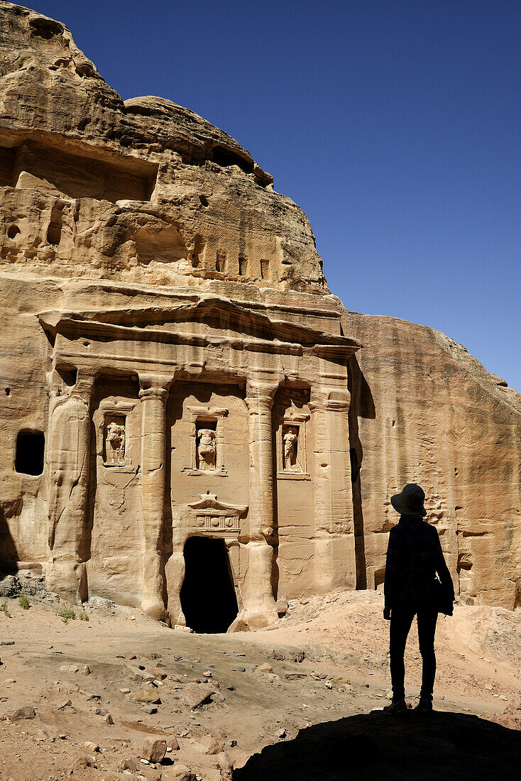 Silhouette of a woman watching the façade of the Roman Soldier´s Tomb, carved out of a sandstone rock face. Jordan (Hashemite Kingdom of), Ma´an Governorate (Maan), ancient city of Petra. Model Released.