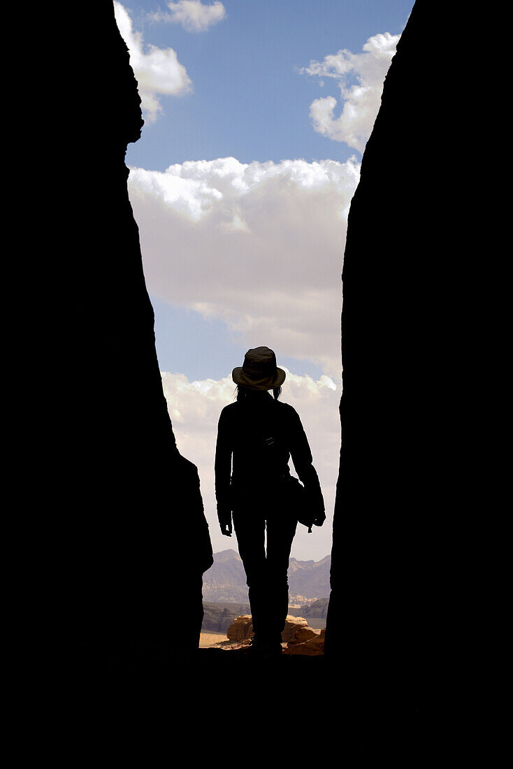 Silhouette of a woman with a hat in a narrow canyon. Jordan, Wadi Rum desert, protected area inscribed on UNESCO World Heritage list. Model Released.