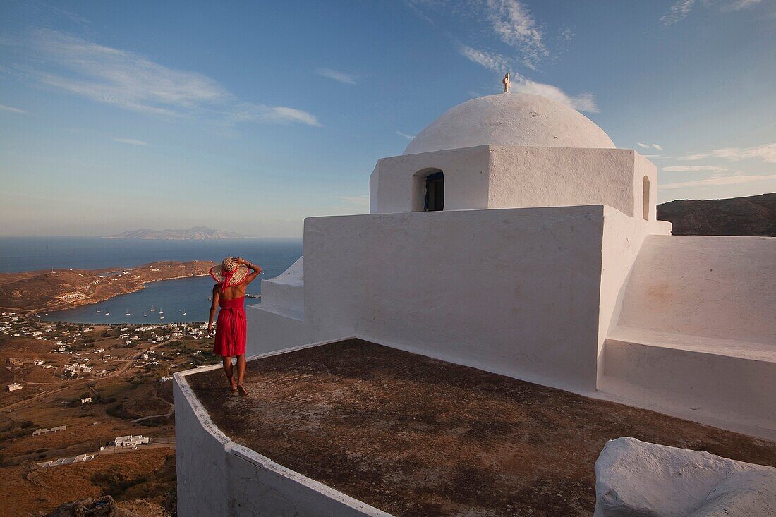 Woman looking down to the port from the stairs of a church in Hora, Serifos, Cyclades Islands, Greek Islands, Greece, Europe.