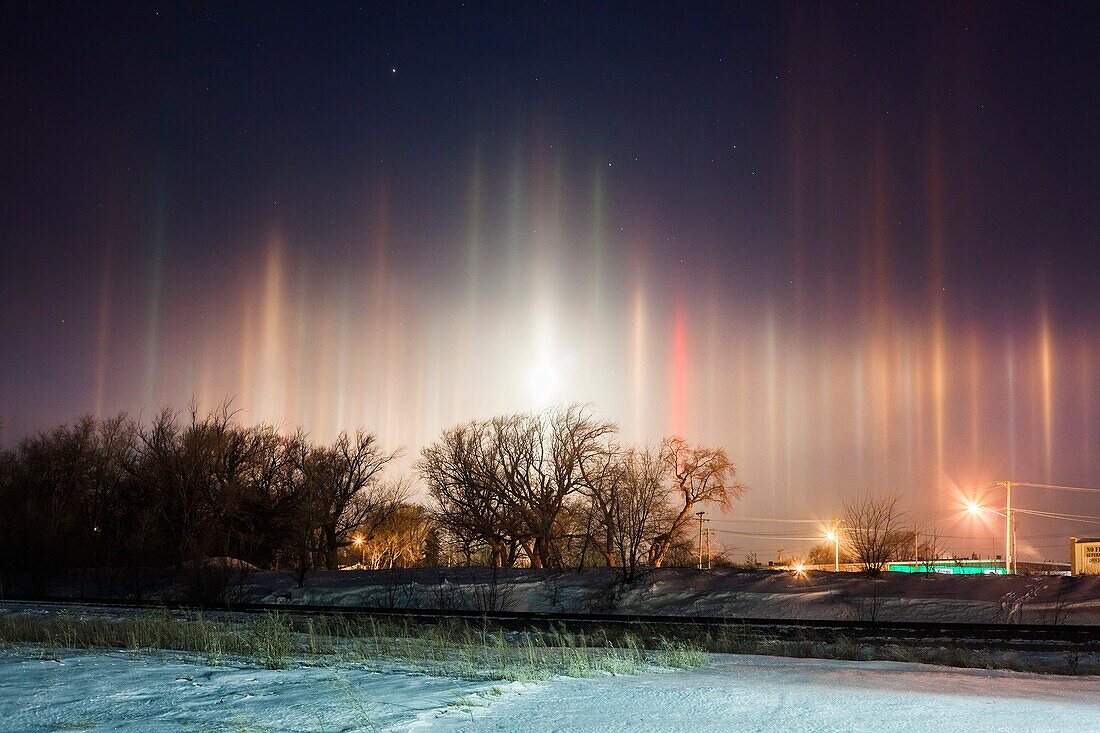 Arctic air combines with river steam and a corn milling plant´s steam to produce light pillars over Blair Nebraska, thanks to ice crystals floating in the air from the steam sources. A setting moon adds to the scene, creating a light pillar of its own.