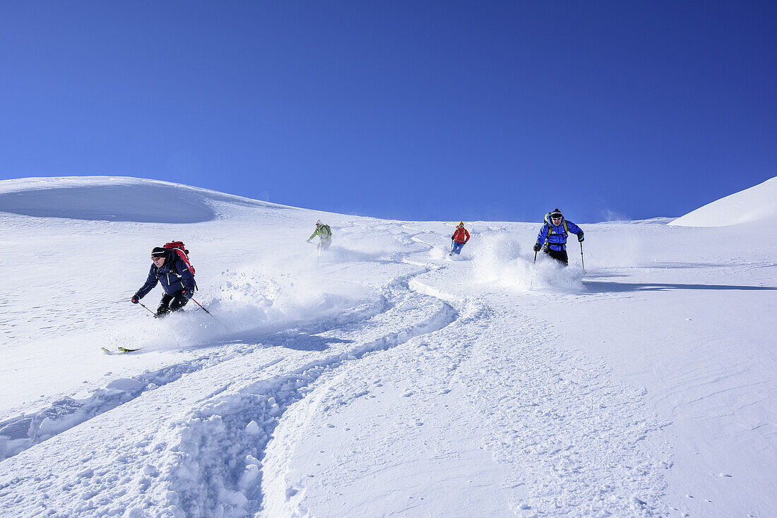 Several persons downhill skiing from Sonnenjoch through deep snow in the back-country, Sonnenjoch, Kitzbuehel Alps, Tyrol, Austria