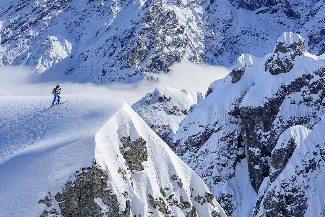 Person back-country skiing ascending to snow-summit in front of rockface, Hochalm, Hochkalter, National Park Berchtesgaden, Berchtesgaden Alps, Berchtesgaden, Upper Bavaria, Bavaria, Germany
