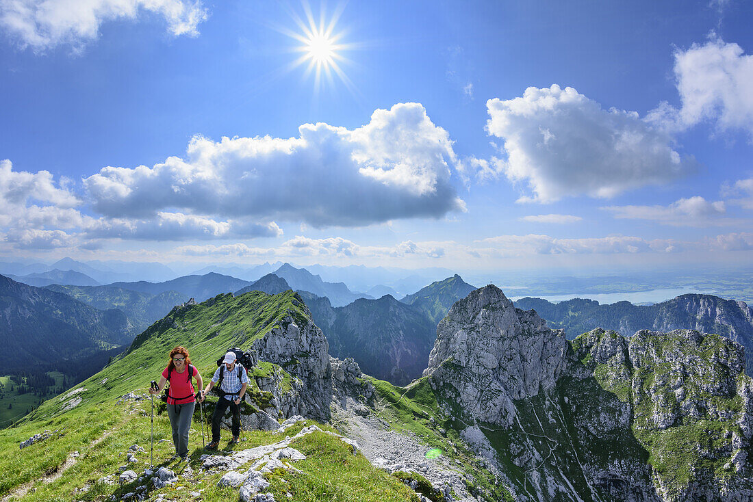 Frau und Mann beim Wandern steigen zur Krähe auf, Säuling, Tegelberg und Gabelschrofen im Hintergrund, Krähe, Ammergauer Alpen, Ammergebirge, Ostallgäu, Allgäu, Schwaben, Bayern, Deutschland