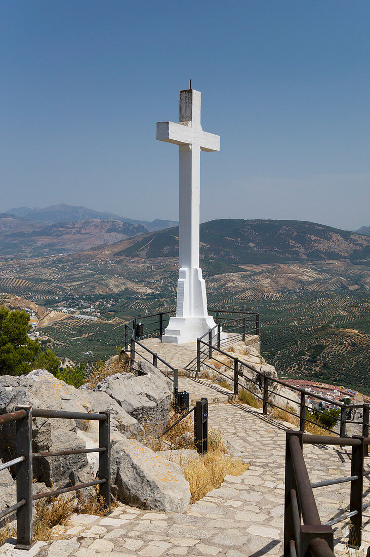 'Walkway with railing to a large, white stone cross with mountains in the distance; Jaen, Spain'
