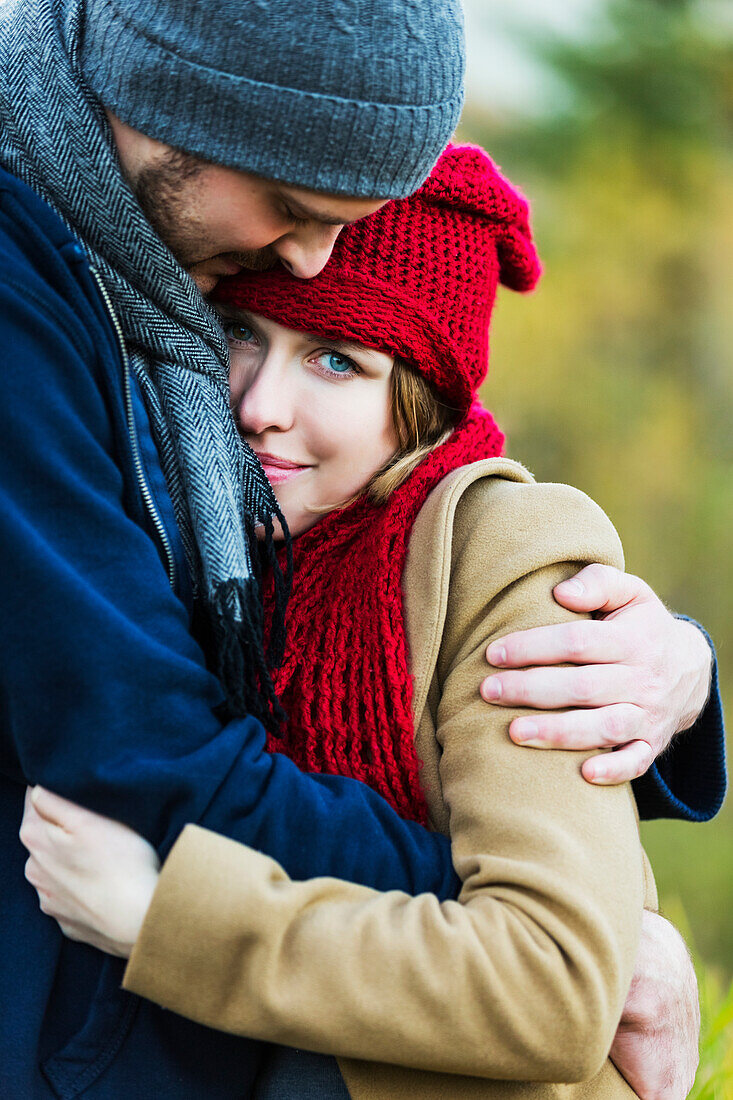 'A young couple holding each other closely in a city park in autumn; Edmonton, Alberta, Canada'