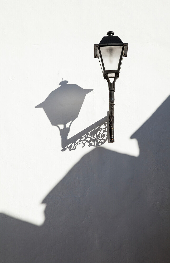 'A light mounted on a white wall with shadows cast; Conil de la Frontera, Andalusia, Spain'