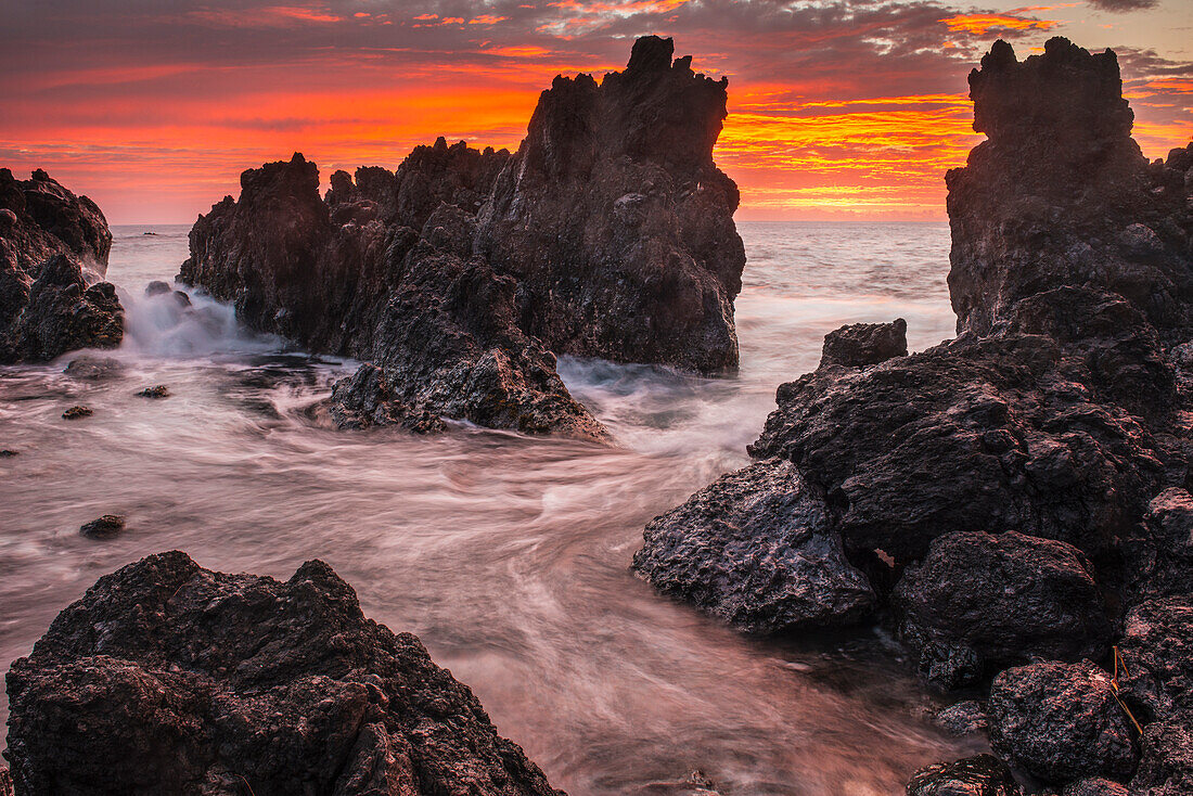 'The colours of sunrise behind coastal lava rocks; Laupahoehoe, Island of Hawaii, Hawaii, United States of America'