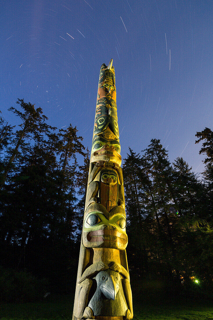 Totem pole lit up at night in Sitka National Historic Park, Southeast Alaska, USA, Summer
